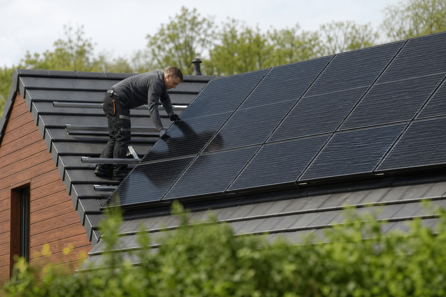 Technicien posant panneaux solaires sur toit en pente