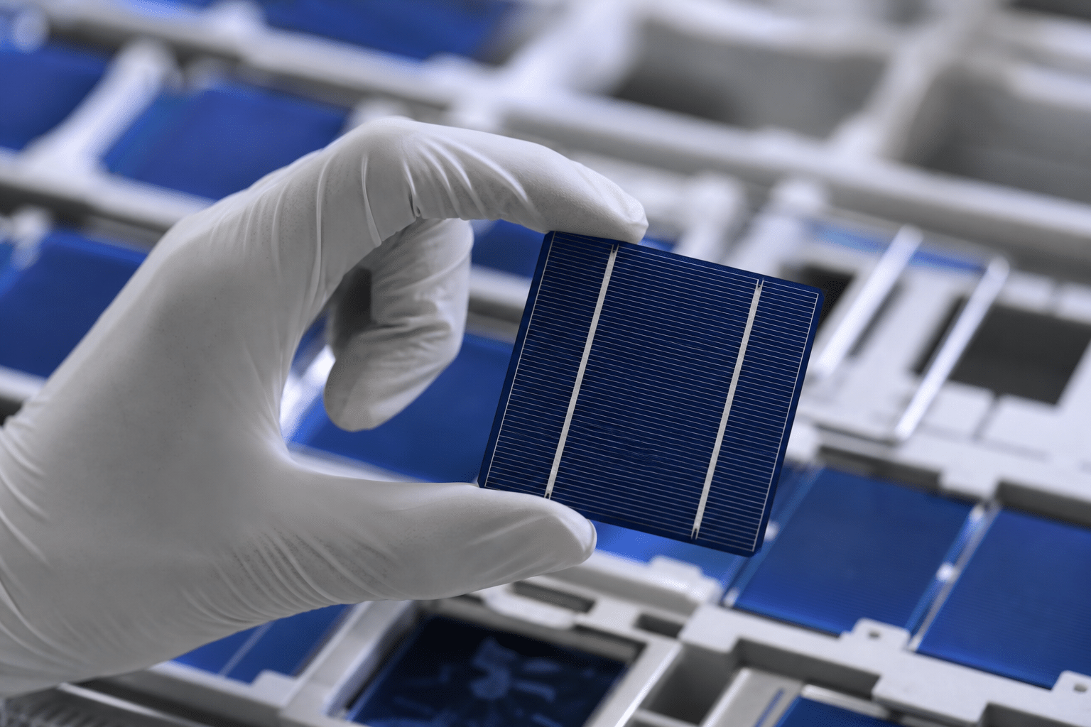 Main gantée tenant une cellule solaire bleue