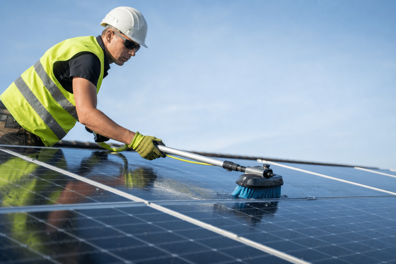Technicien nettoyant panneaux solaires avec brosse